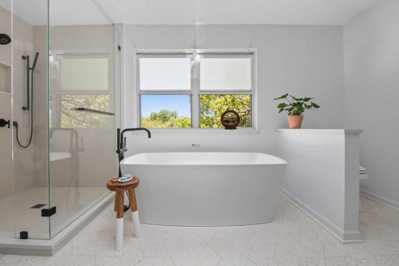 A bathroom with a tub , shower and window.