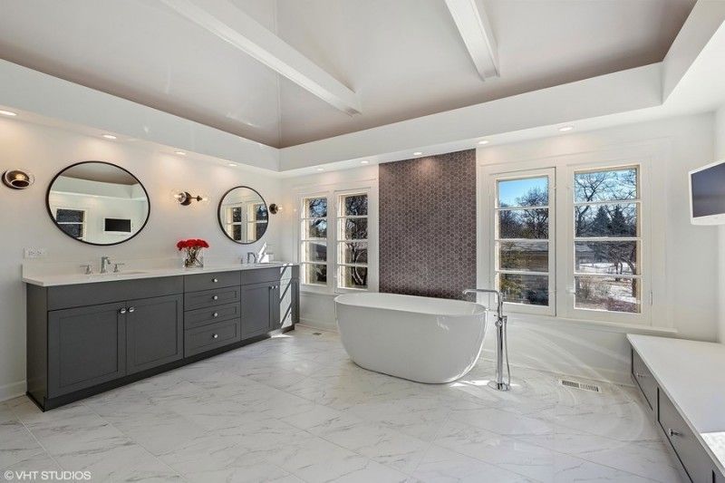 A bathroom with two sinks , a tub and two mirrors.