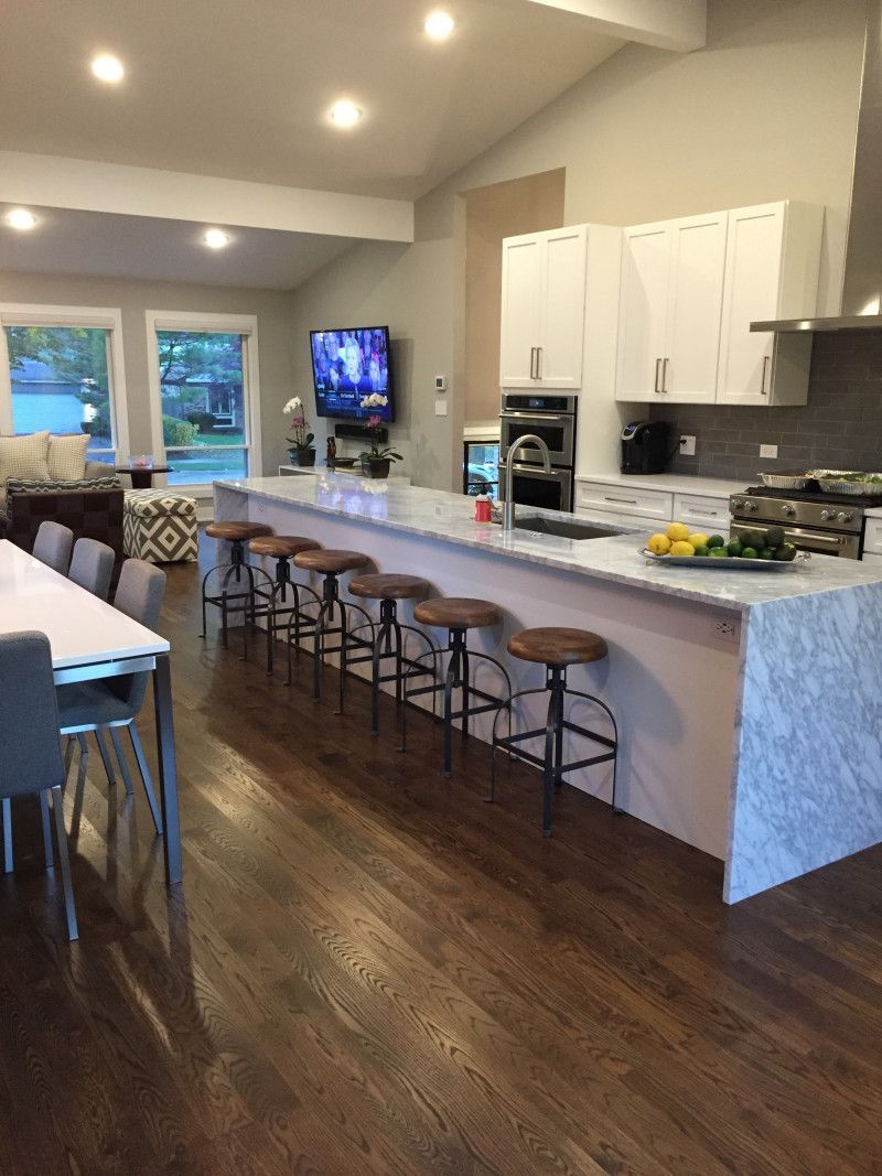 A kitchen with a long island , stools , a table and a television.