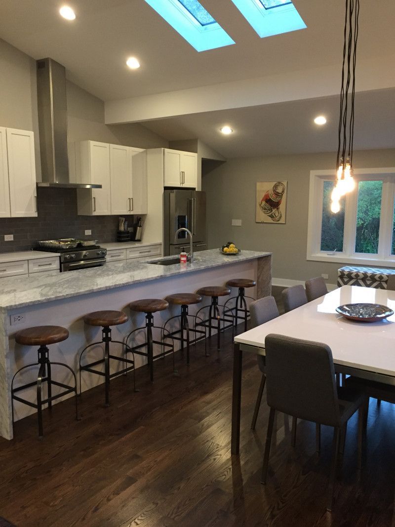 A kitchen with a table and chairs and a skylight above the counter.