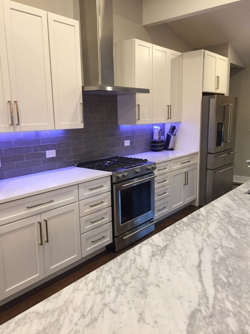 A kitchen with white cabinets , stainless steel appliances , and marble counter tops.