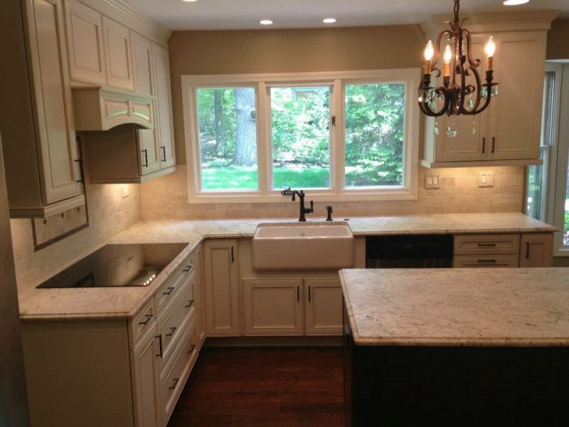 A kitchen with white cabinets a sink and a chandelier