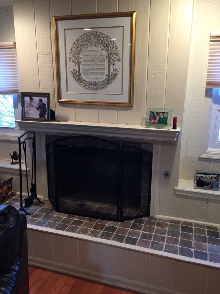 A living room with a fireplace and a picture on the wall above it