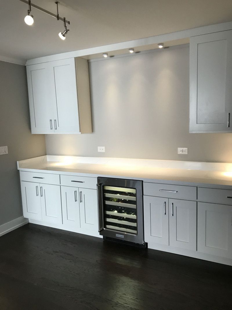 A kitchen with white cabinets and a wine cooler