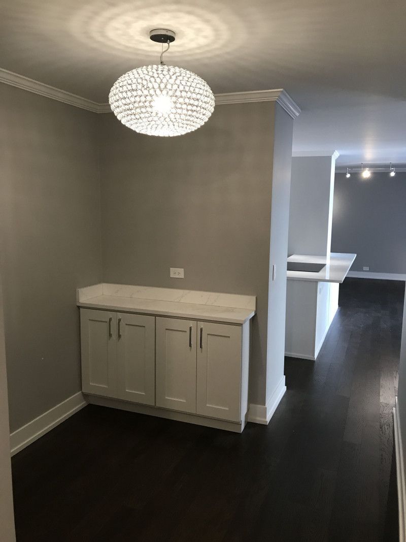 An empty room with white cabinets and a light hanging from the ceiling