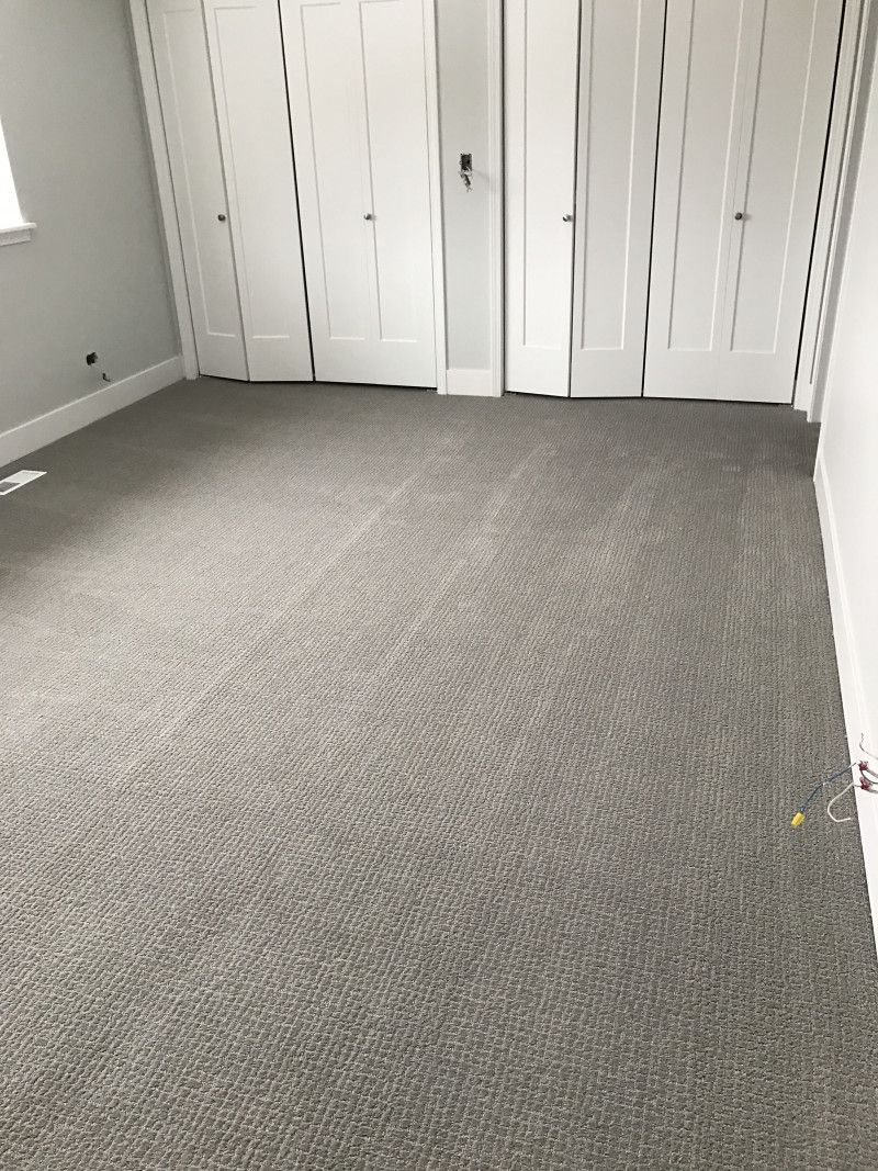 An empty room with a carpeted floor and white walls.