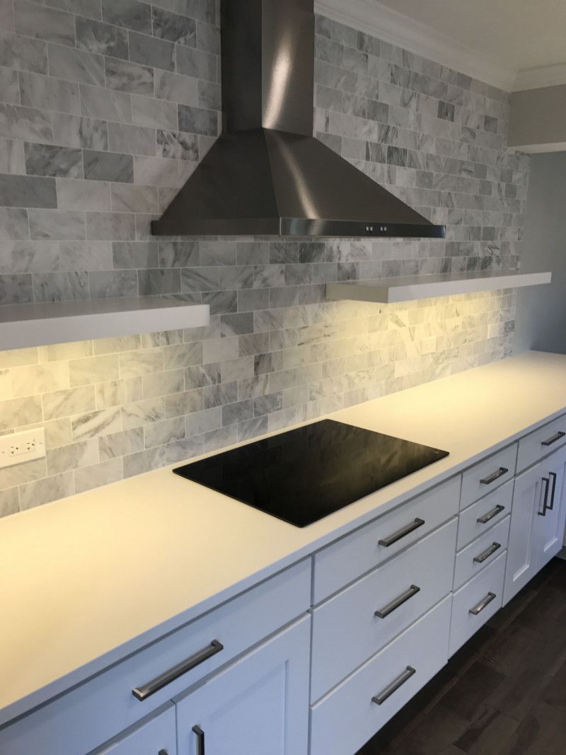 A kitchen with white cabinets and a black stove top oven