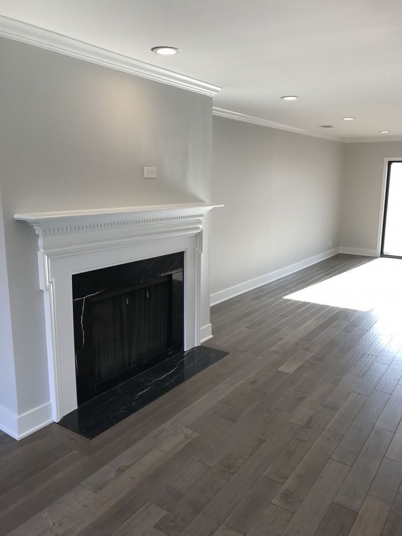 An empty living room with a fireplace and hardwood floors.
