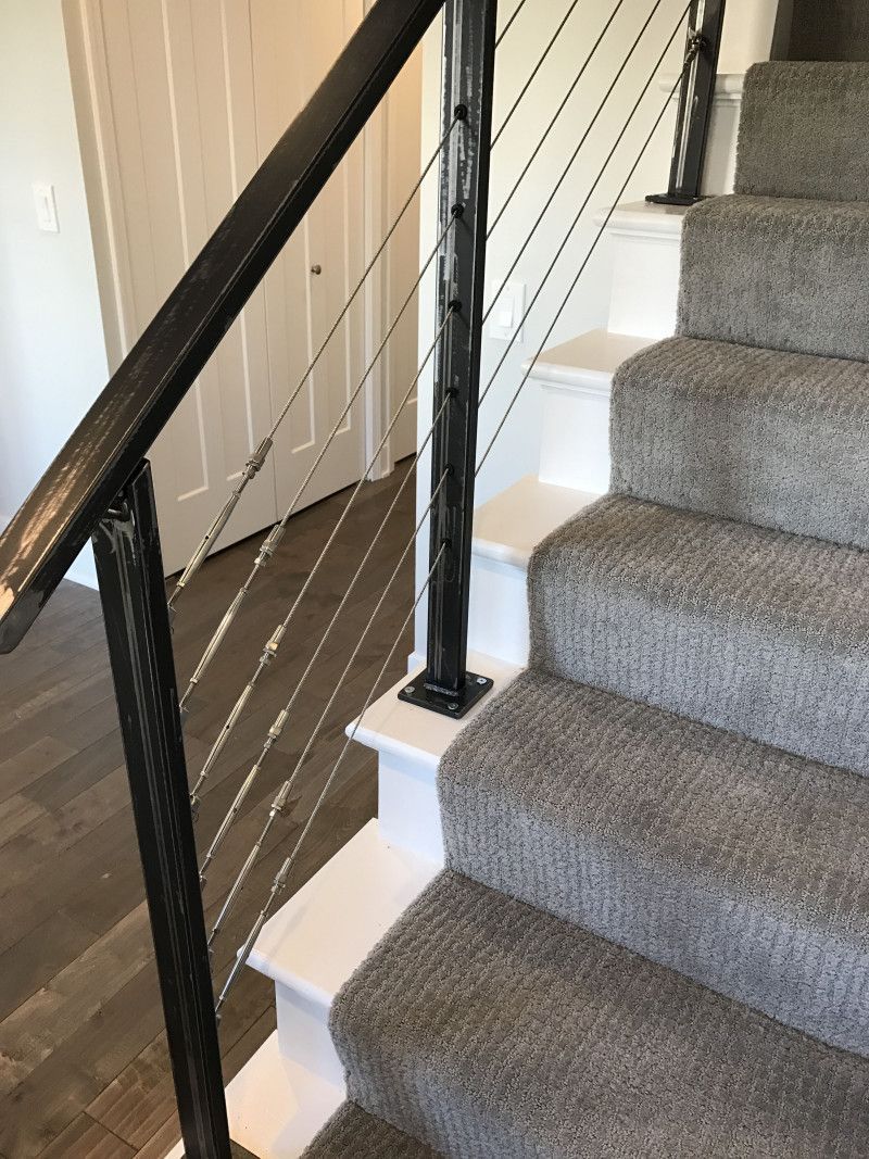 A staircase with a gray carpet and a black railing.