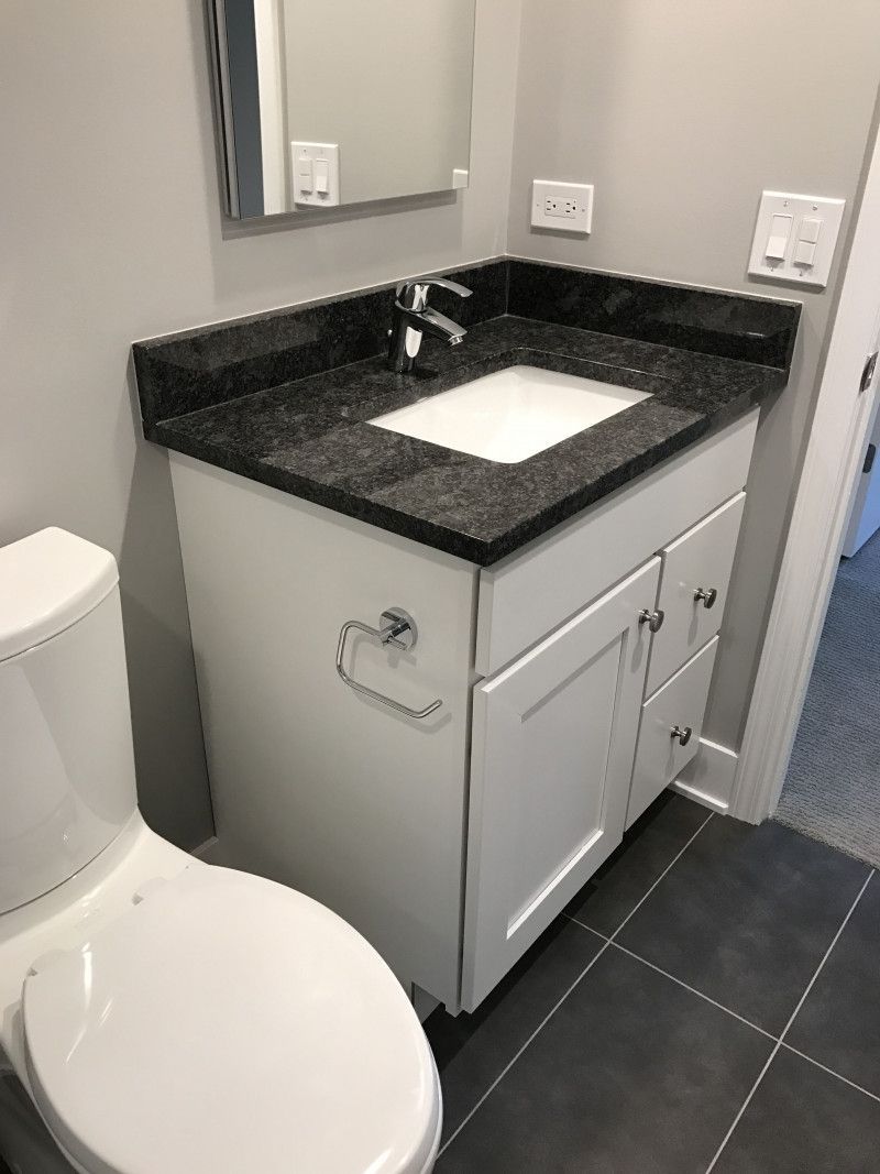 A bathroom with a toilet , sink and mirror.