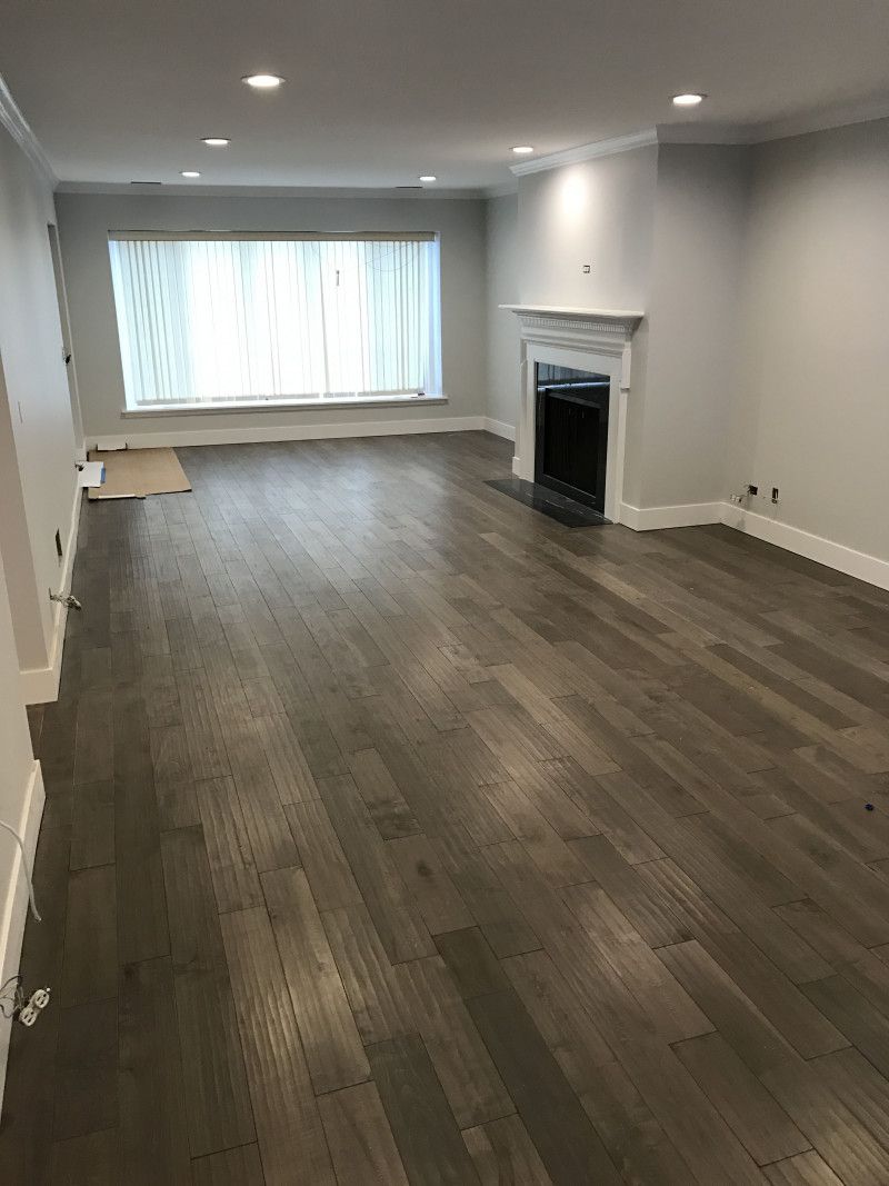 An empty living room with hardwood floors and a fireplace.