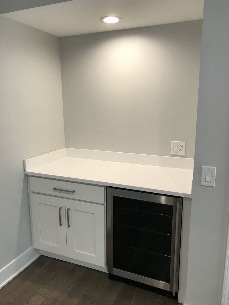 A kitchen with white cabinets and a stainless steel refrigerator.