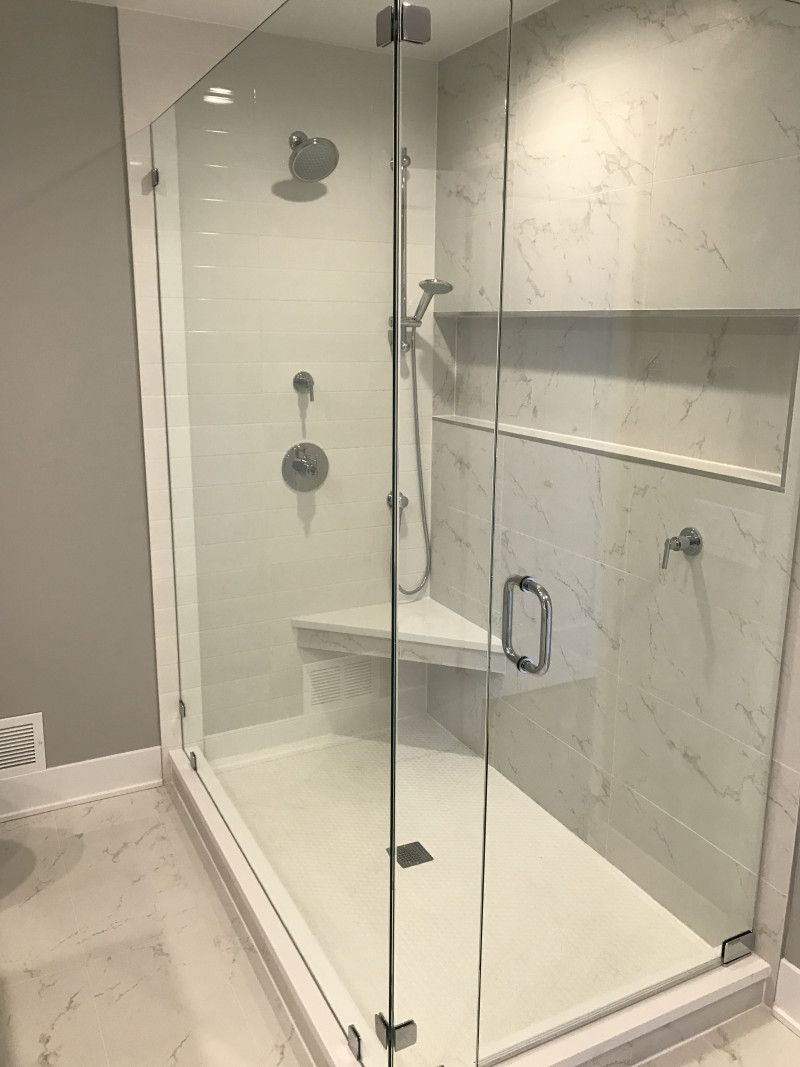 A bathroom with a walk in shower with a glass door.