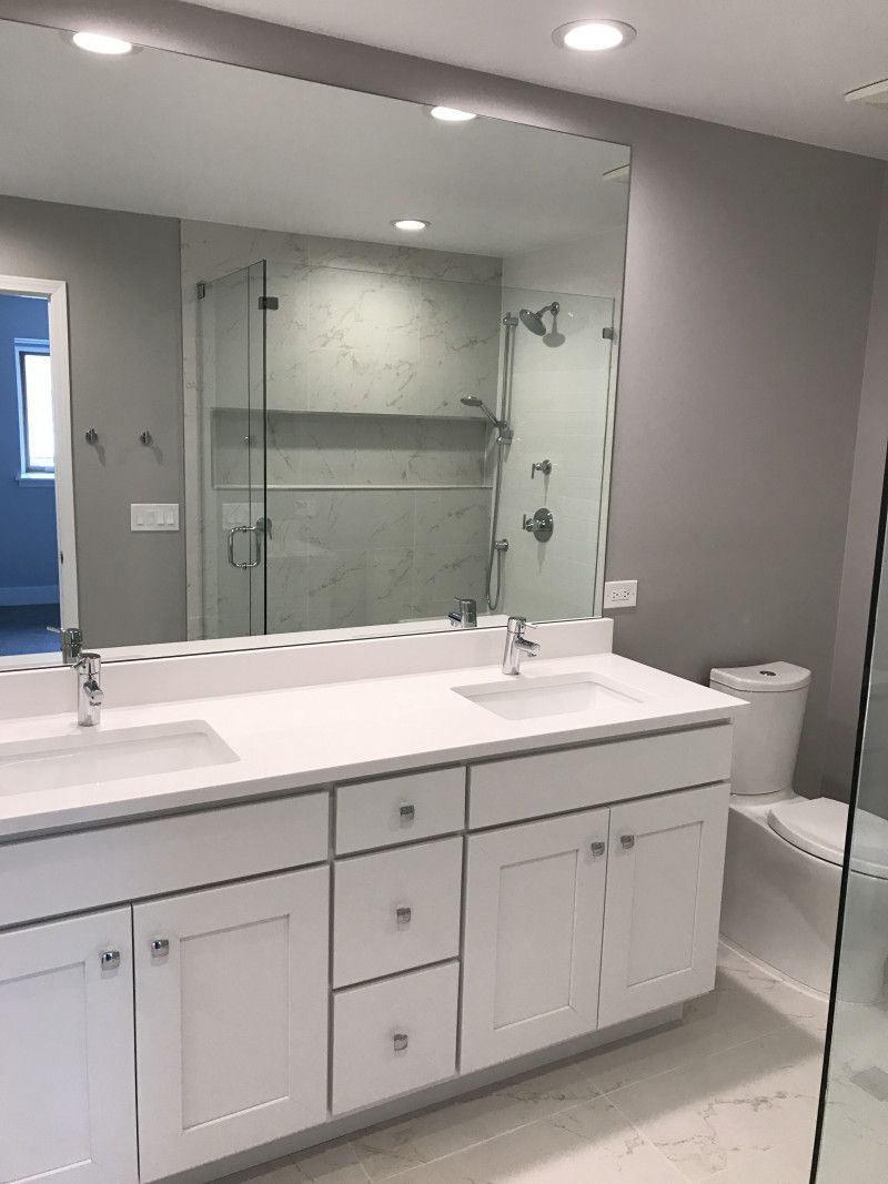 A bathroom with two sinks , a toilet , and a large mirror.