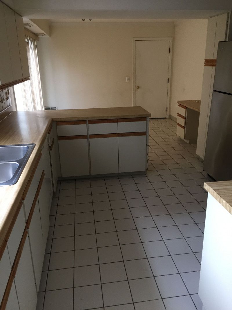 An empty kitchen with a sink and a refrigerator