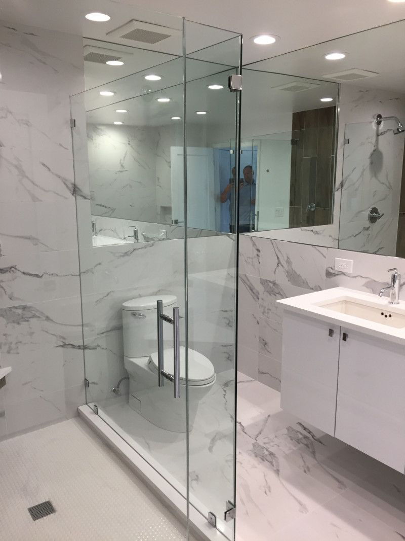 A bathroom with a toilet , sink , mirror and shower stall.