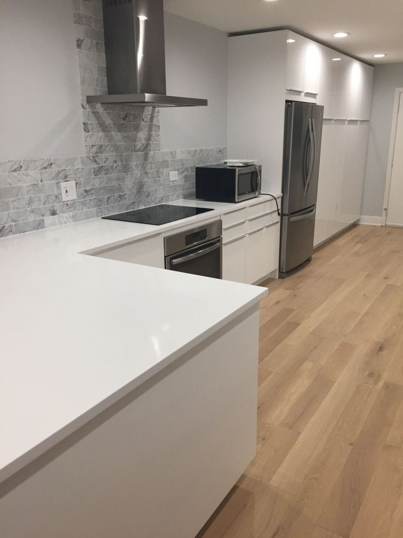 A kitchen with white cabinets , stainless steel appliances , and wooden floors.
