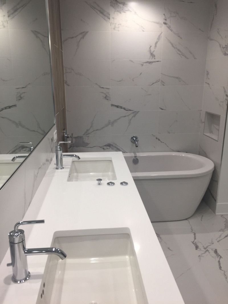 A bathroom with a sink , tub and mirror.