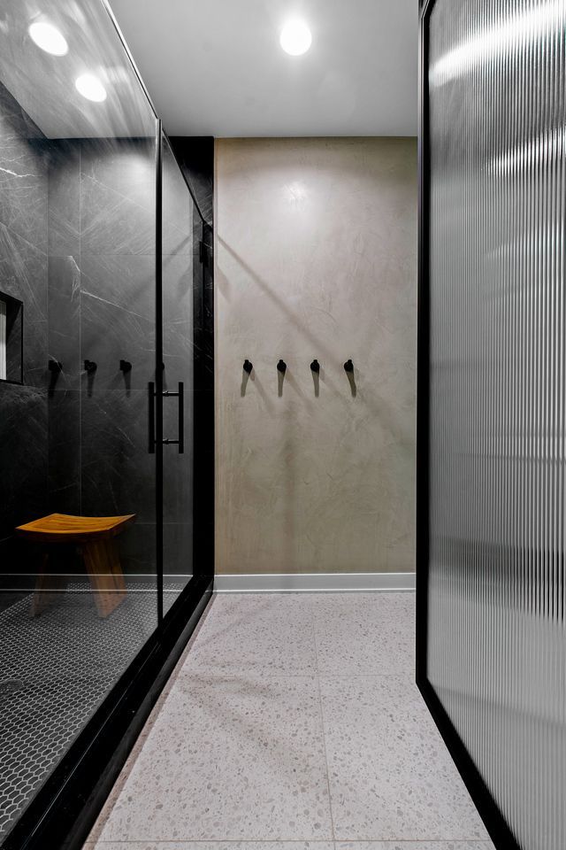 A hallway with a glass door and hooks on the wall.