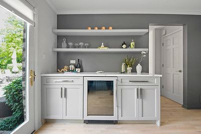 A kitchen with white cabinets , a refrigerator and shelves.