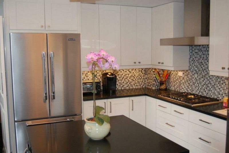 A kitchen with white cabinets and a stainless steel refrigerator