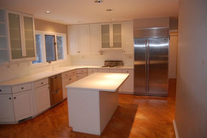 An empty kitchen with white cabinets and stainless steel appliances
