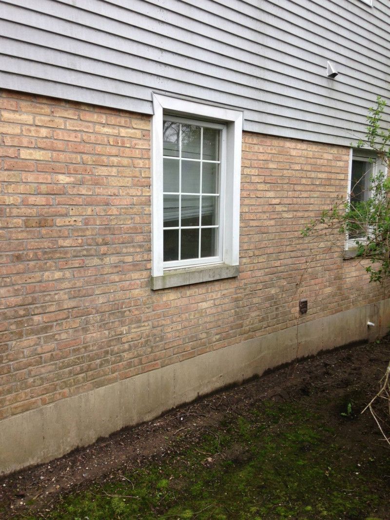 A brick house with a window on the side of it.