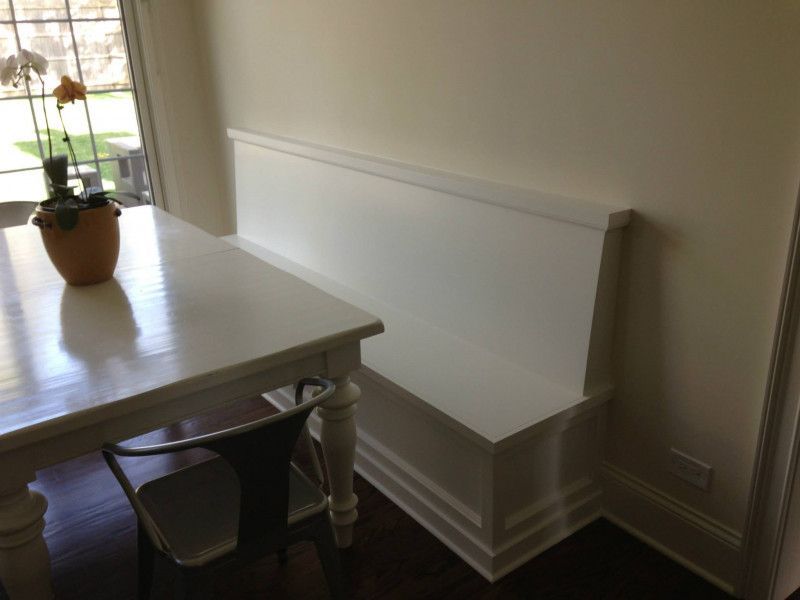 A white table with a bench underneath it