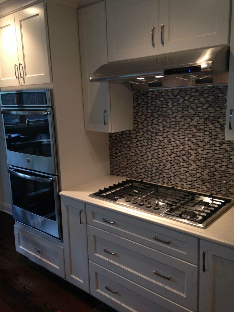 A kitchen with white cabinets , stainless steel appliances and a stove top oven.