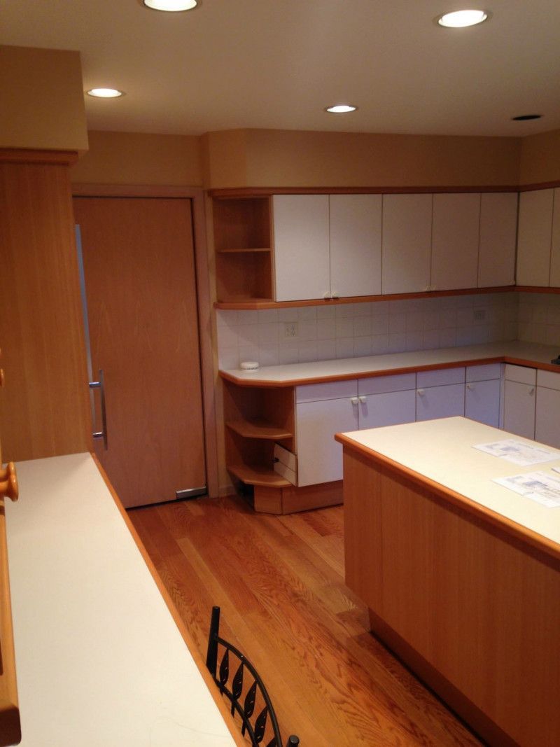 A kitchen with wooden cabinets and white counter tops