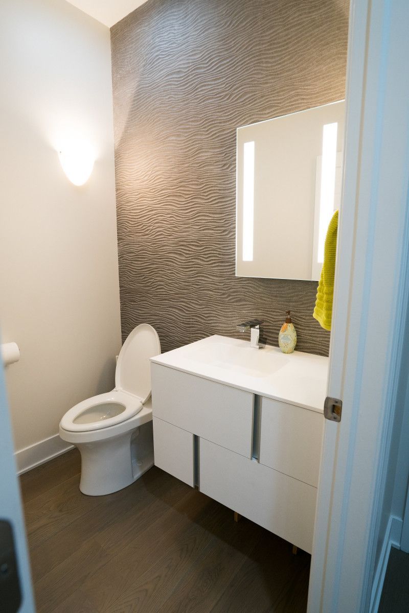 A bathroom with a toilet , sink and mirror.