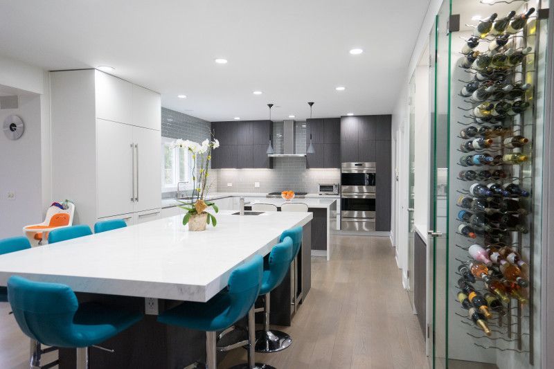 A kitchen with a large island and blue chairs and a wine rack.