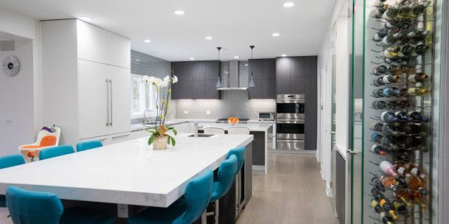 A kitchen with a large island and blue chairs and a wine cellar.