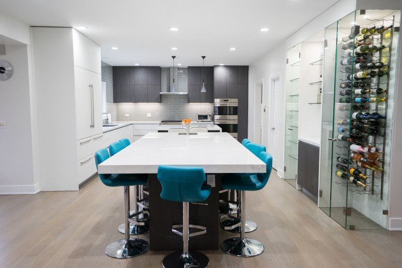 A kitchen with a long table and blue chairs and a wine cellar.