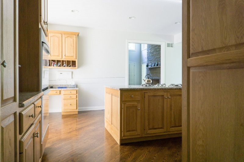A kitchen with wooden cabinets and a large island in the middle of the room.
