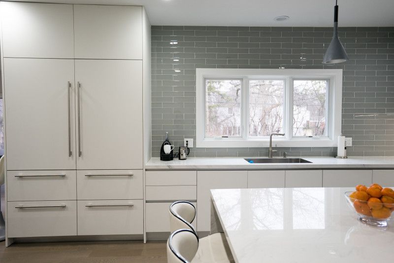 A kitchen with white cabinets , a sink , and a large window.