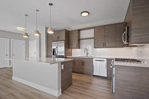 A kitchen with wooden cabinets , stainless steel appliances , and a large island.