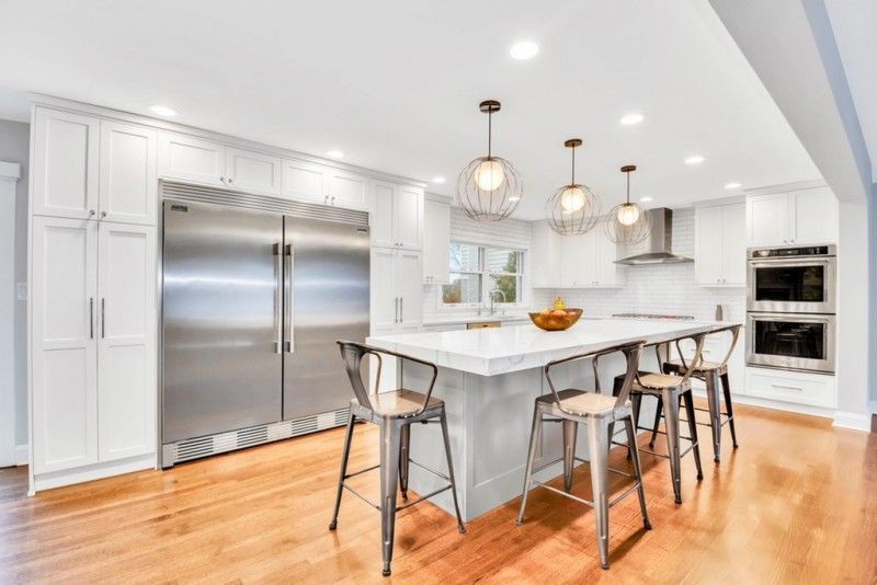 A kitchen with white cabinets and stainless steel appliances and a large island.