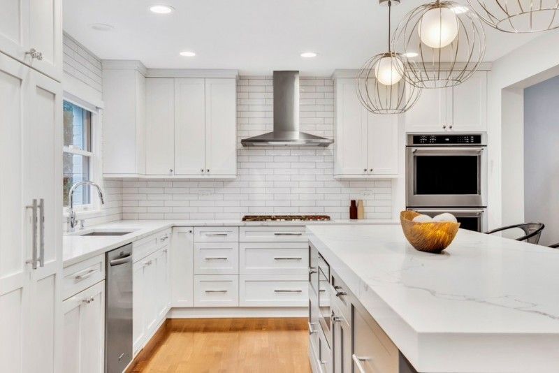 A kitchen with white cabinets , stainless steel appliances , and a large island.
