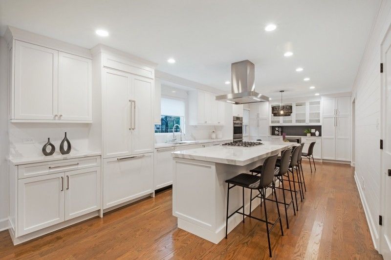 A kitchen with white cabinets and hardwood floors and a large island.