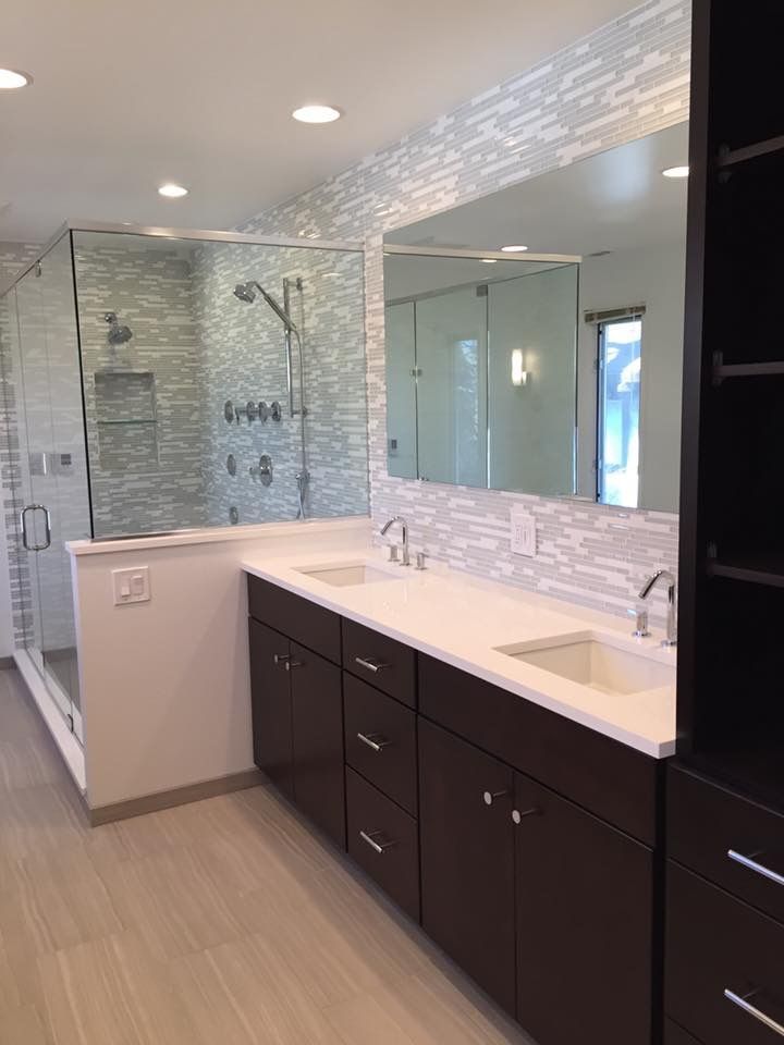 A bathroom with two sinks , a shower and a large mirror.