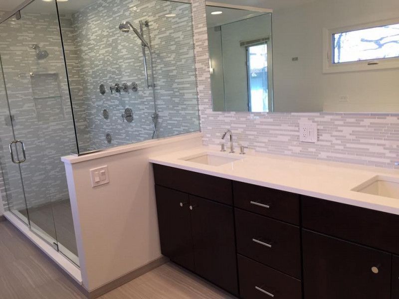 A bathroom with a sink , mirror and walk in shower.