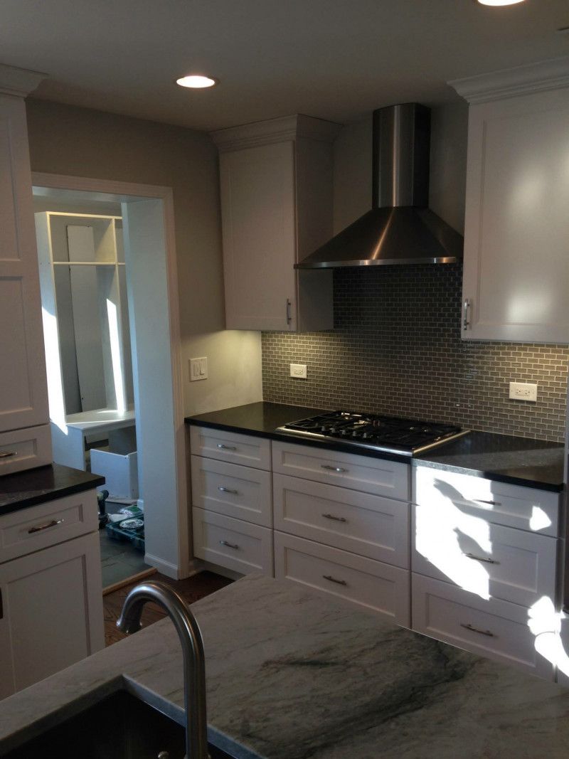 A kitchen with white cabinets and black counter tops
