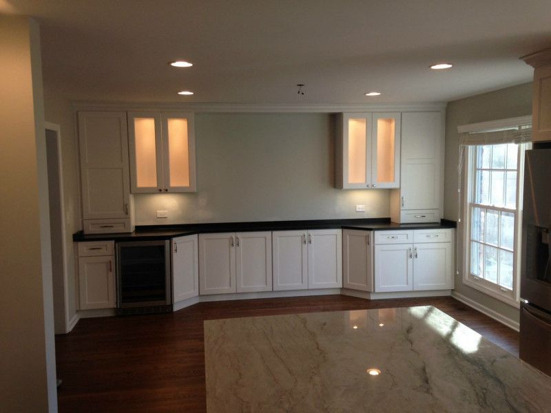 An empty kitchen with white cabinets and black counter tops