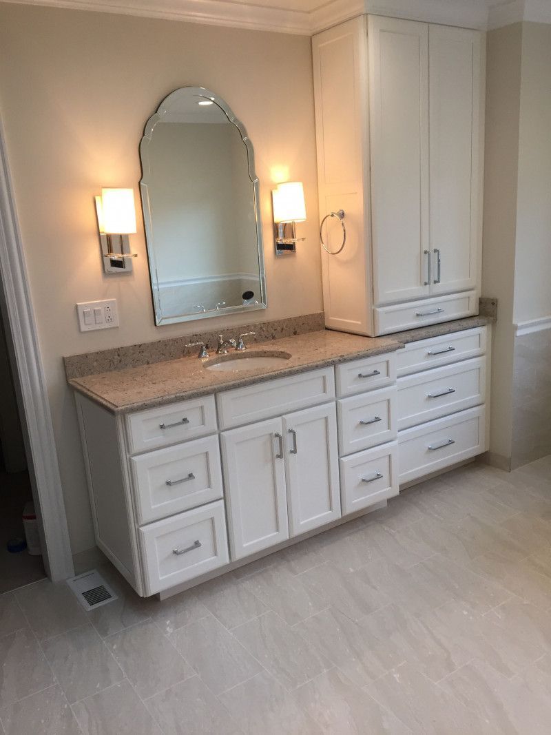A bathroom with a sink , mirror , cabinets and drawers.