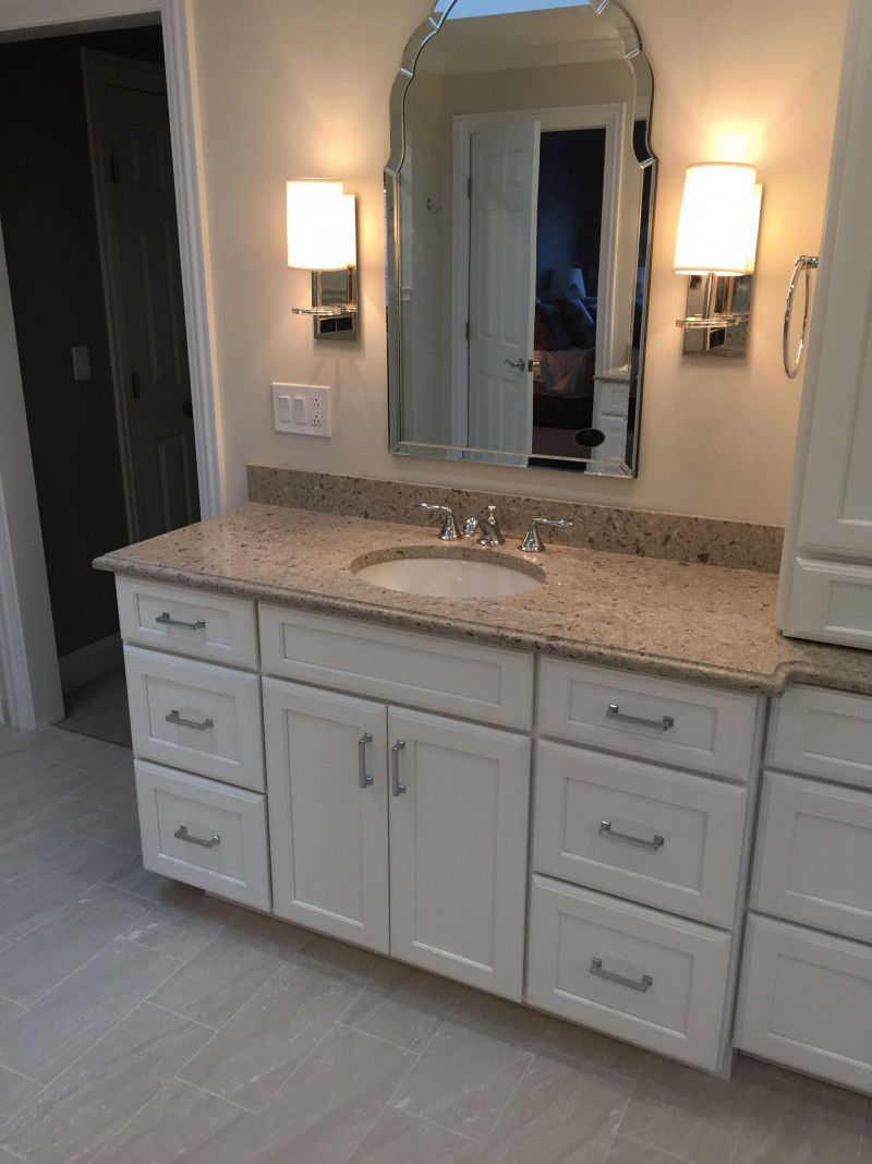 A bathroom with a sink , cabinets , drawers and a mirror.