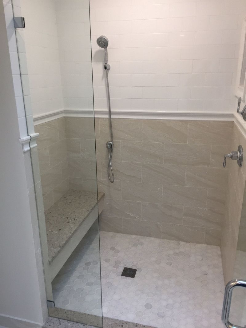 A bathroom with a walk in shower and a bench.
