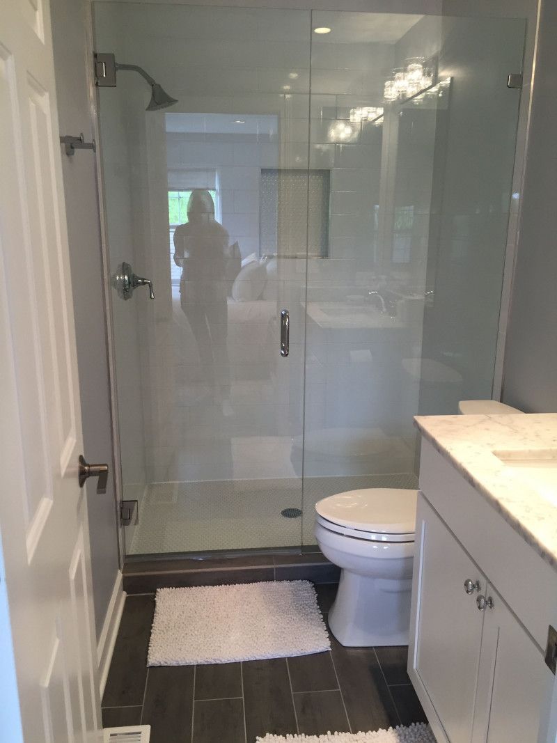 A bathroom with a toilet , sink , shower and glass door.