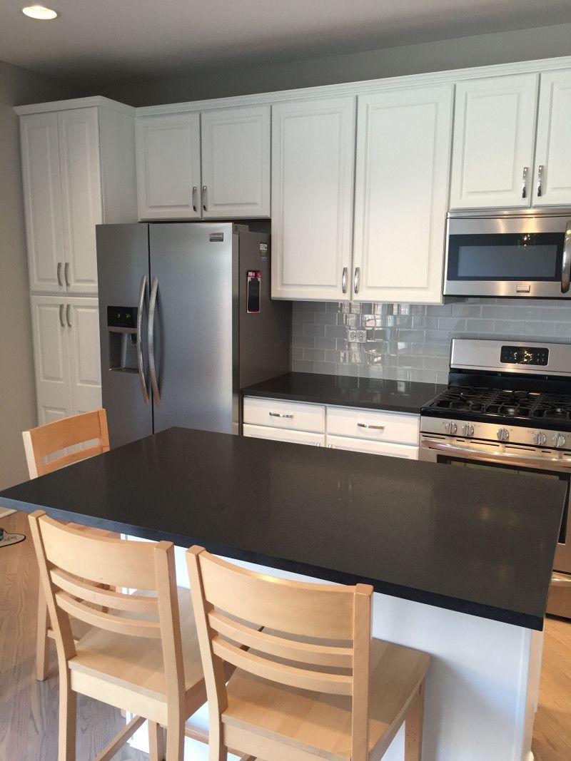 A kitchen with white cabinets and a black counter top