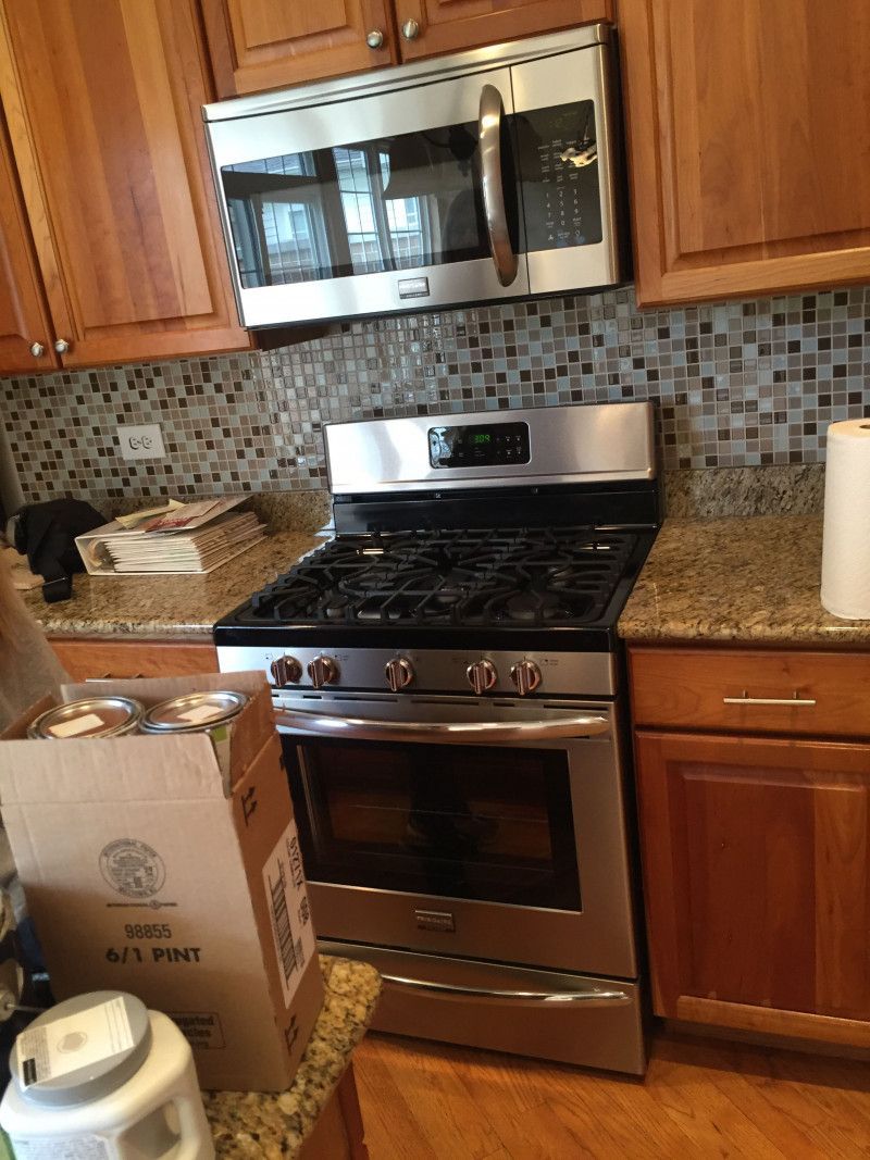 A kitchen with a stove , microwave , and cabinets.